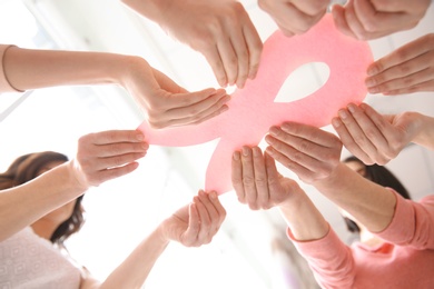 Photo of Women holding pink paper ribbon, bottom view. Breast cancer awareness concept