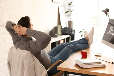 Photo of Young man relaxing at table in office during break