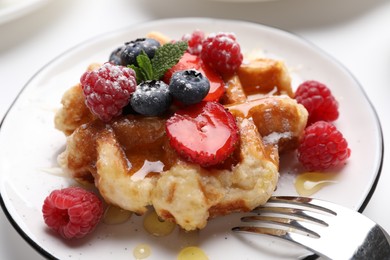 Photo of Delicious Belgian waffle with fresh berries and honey on table, closeup