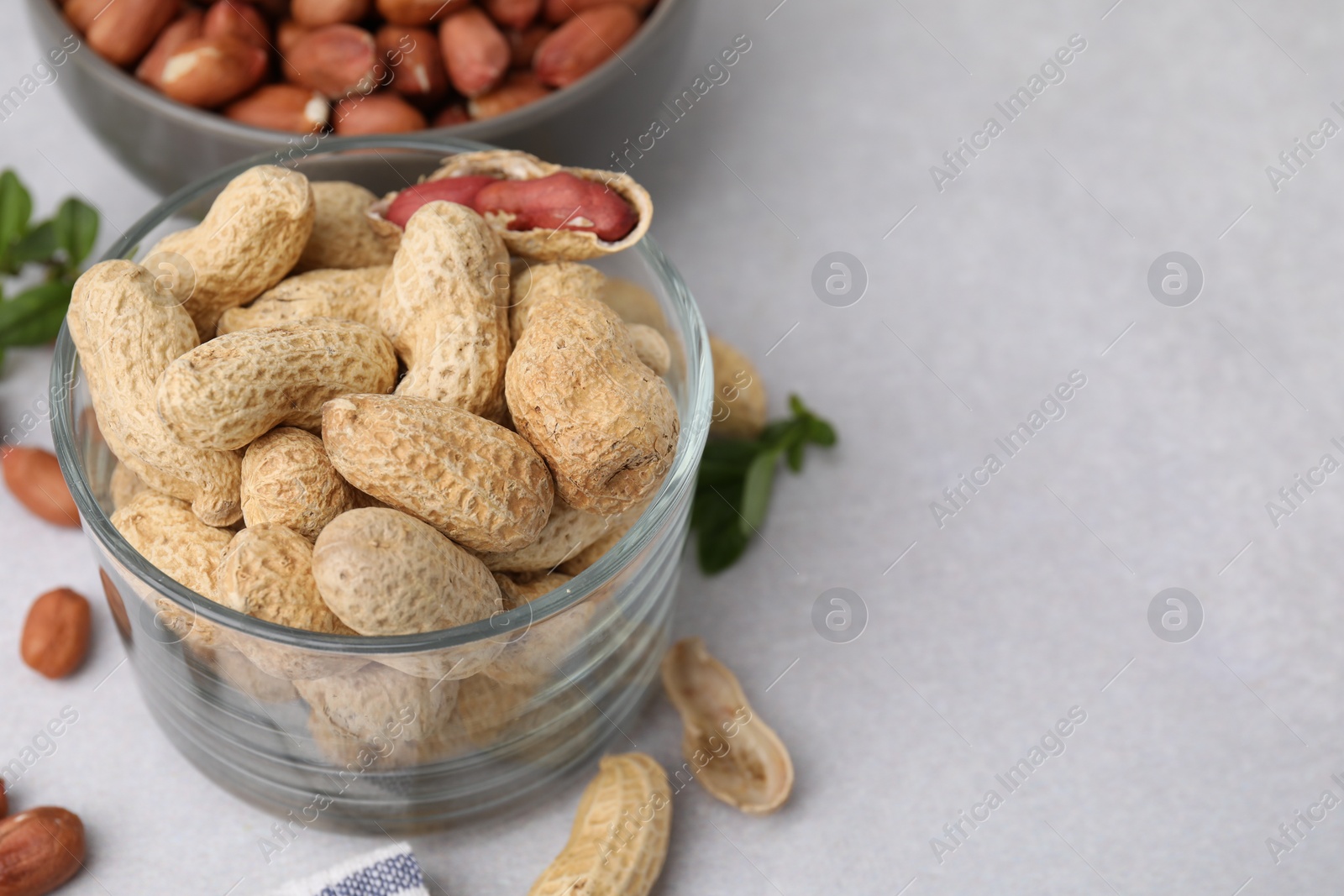 Photo of Fresh unpeeled peanuts on grey table, closeup. Space for text