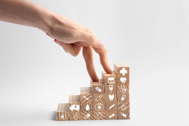 Woman and stairs made with wooden cubes on white background, closeup. Health insurance concept