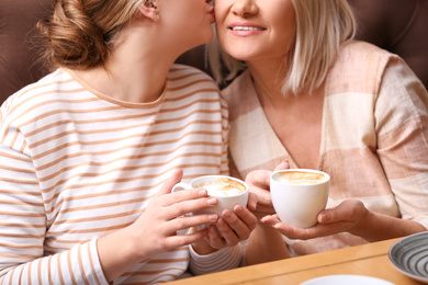 Photo of Mother and her adult daughter spending time together in cafe, closeup