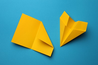 Photo of Handmade yellow plane and folded paper on light blue background, flat lay