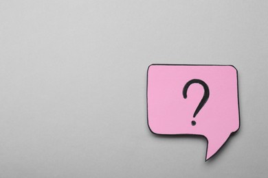 Photo of Paper speech bubble with question mark on light grey background, top view. Space for text