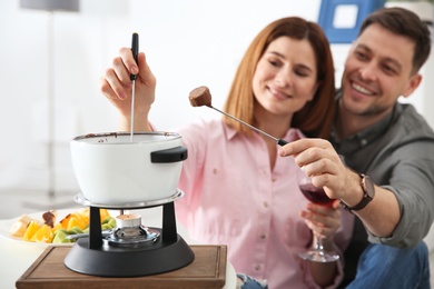 Photo of Happy couple enjoying fondue dinner at home