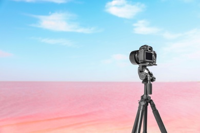Professional camera on tripod near pink lake