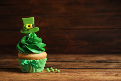 Photo of Delicious decorated cupcake on wooden table, space for text. St. Patrick's Day celebration