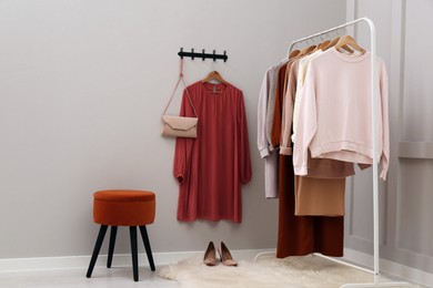 Photo of Rack with different stylish clothes and shoes near grey wall in room