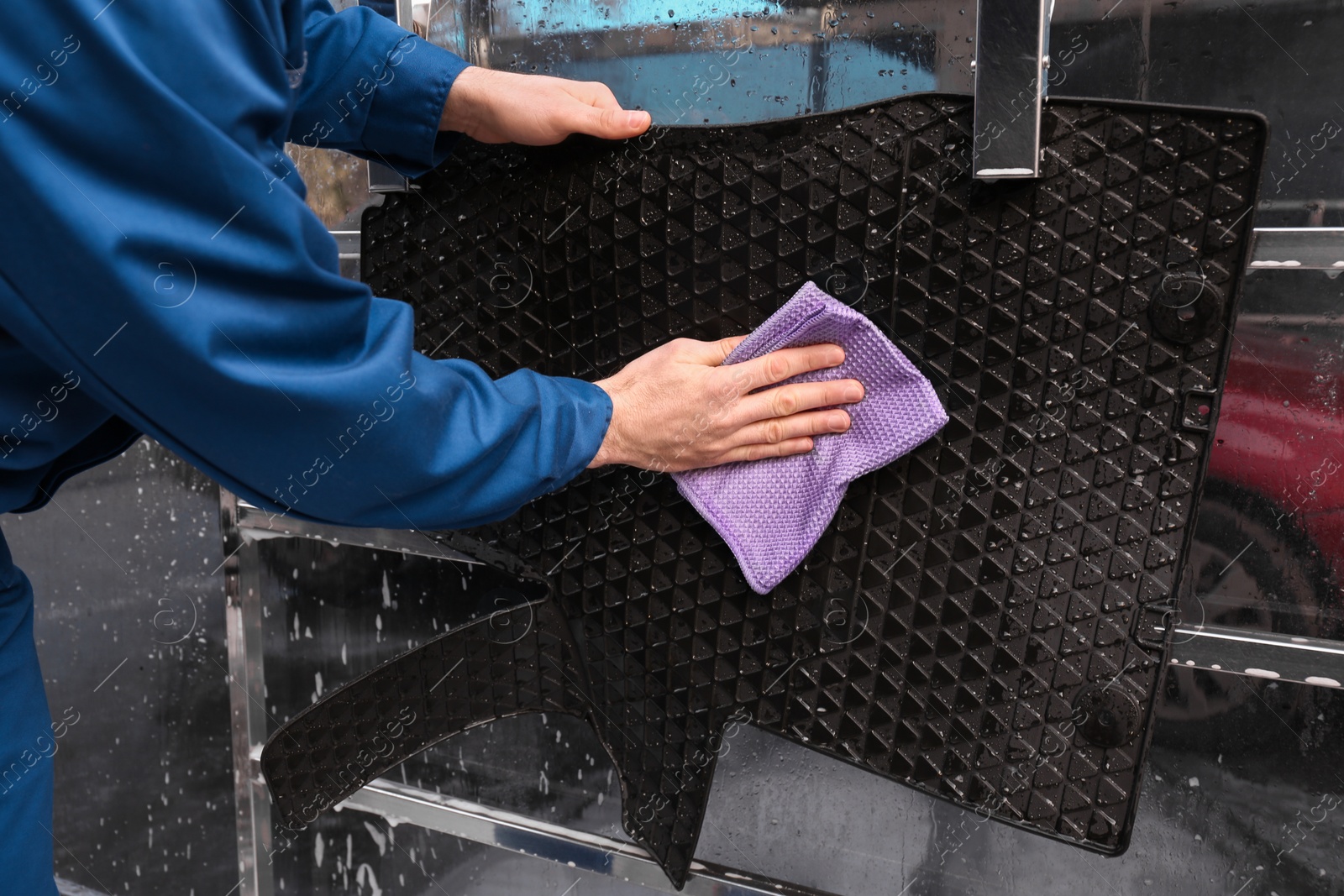 Photo of Worker wiping automobile floor mat at car wash, closeup