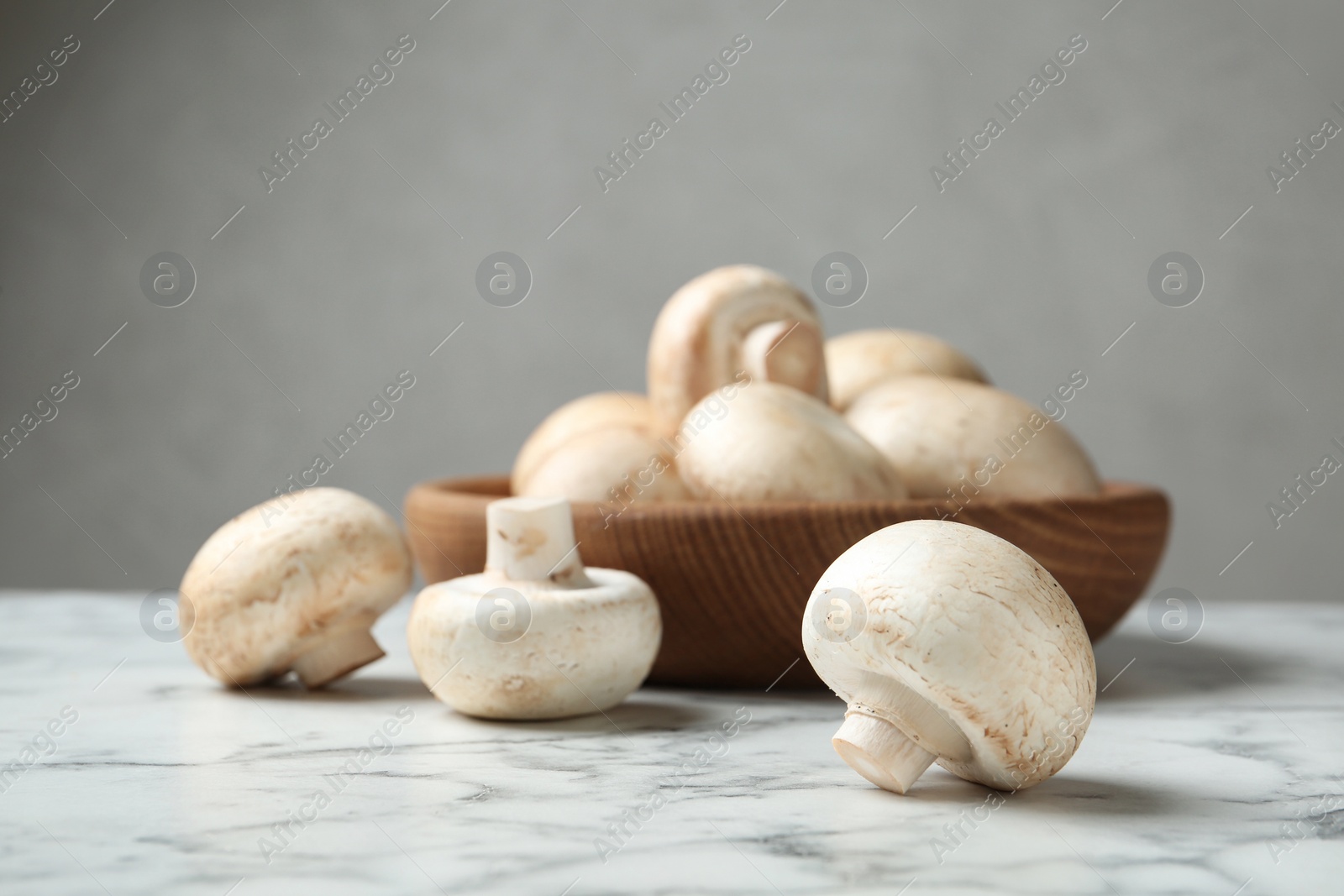 Photo of Fresh champignon mushrooms on marble table, space for text