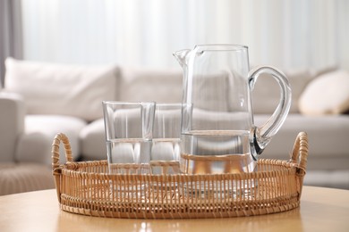 Jug and glasses with clear water on table indoors, closeup