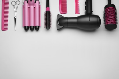 Flat lay composition with modern hair dryer and triple curling iron on white background, space for text