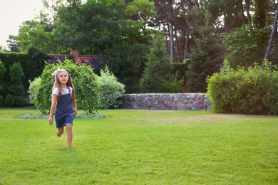 Cute little girl running in green park on summer day