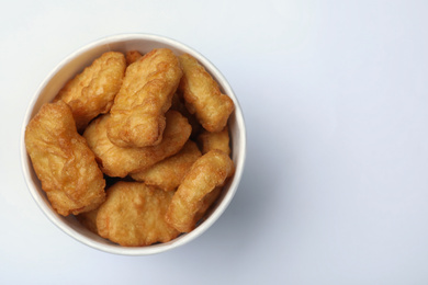 Bucket with tasty chicken nuggets on white background, top view