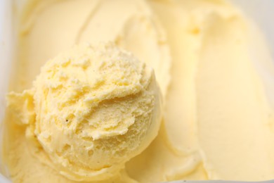Photo of Scoop of delicious vanilla ice cream in container, closeup