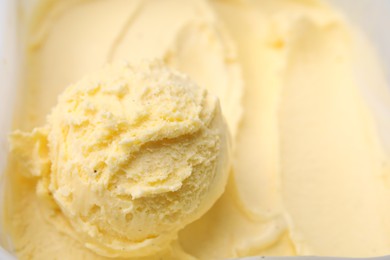 Scoop of delicious vanilla ice cream in container, closeup