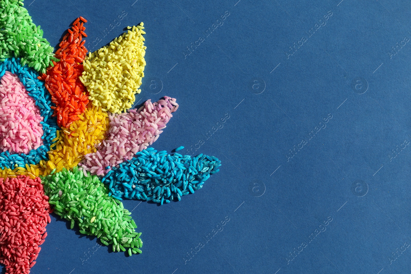 Photo of Diwali celebration. Colorful rangoli on blue background, top view. Space for text