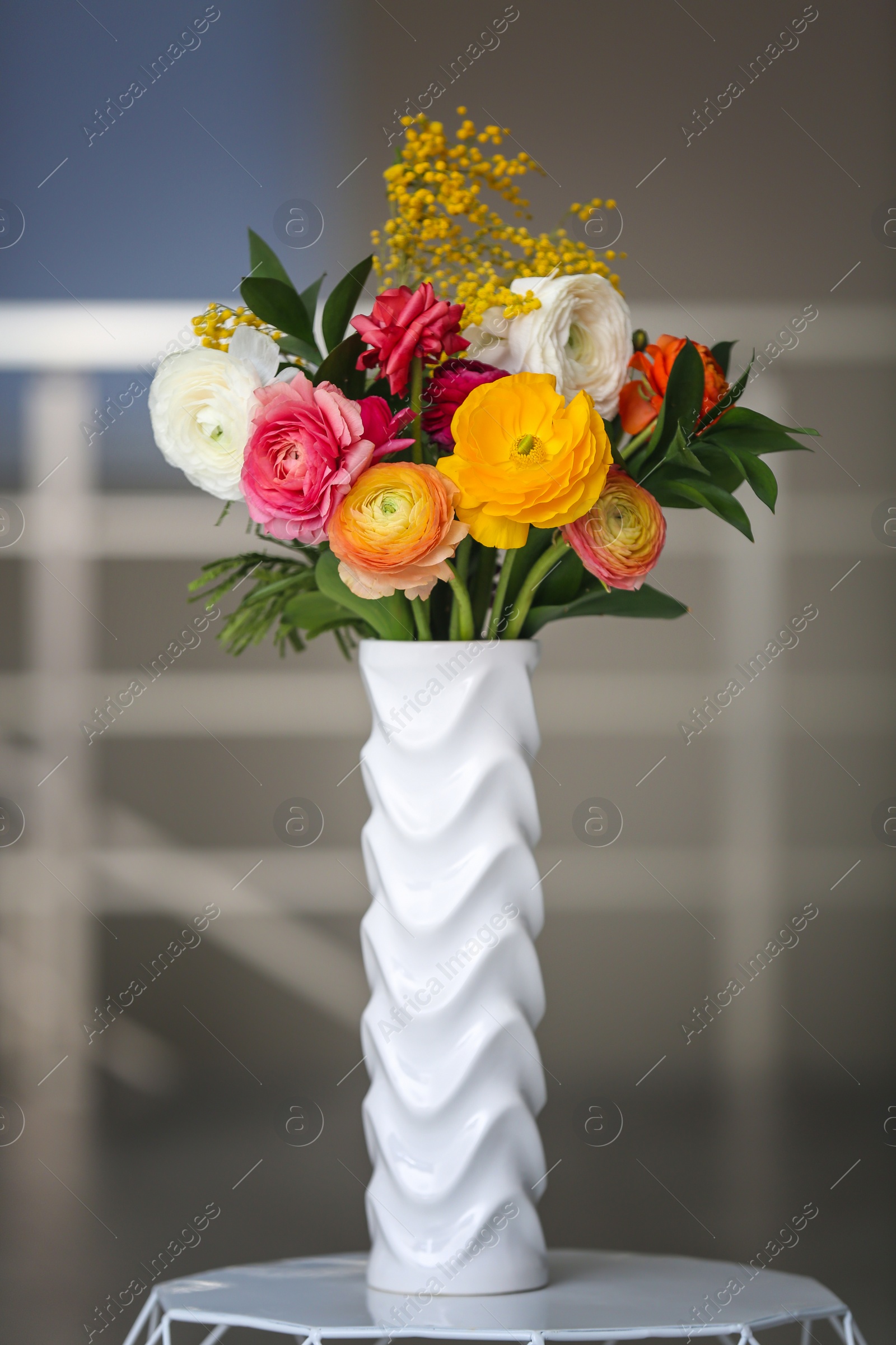 Photo of Vase with beautiful ranunculus flowers on blurred background