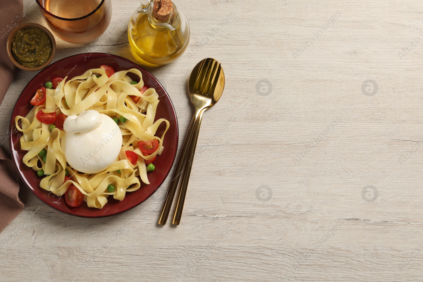 Photo of Plate of delicious pasta with burrata, peas and tomatoes served on white wooden table, flat lay. Space for text