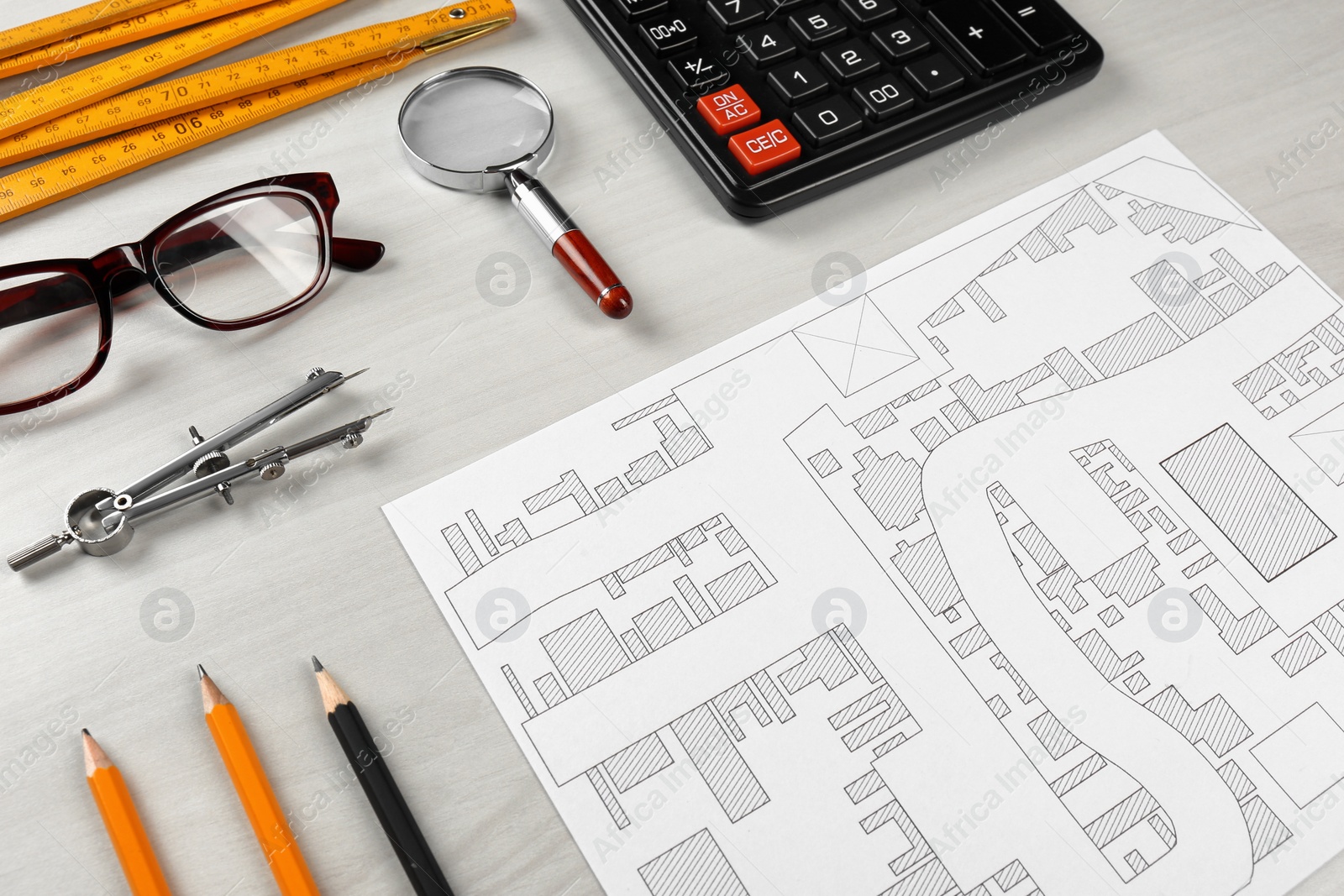 Photo of Office stationery and cadastral map of territory with buildings on white wooden table