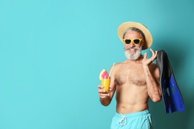 Photo of Shirtless man with glass of cocktail and flippers on color background