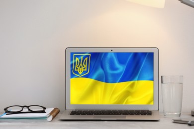Image of Modern laptop with picture of Ukrainian national flag on screen