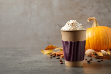 Photo of Paper cup with tasty pumpkin spice latte on grey table. Space for text
