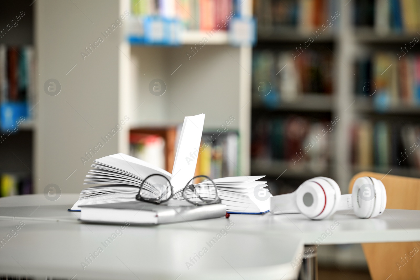 Photo of Books, glasses and headphones on table in library