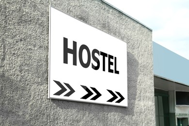 HOSTEL sign board with arrows on building facade outdoors