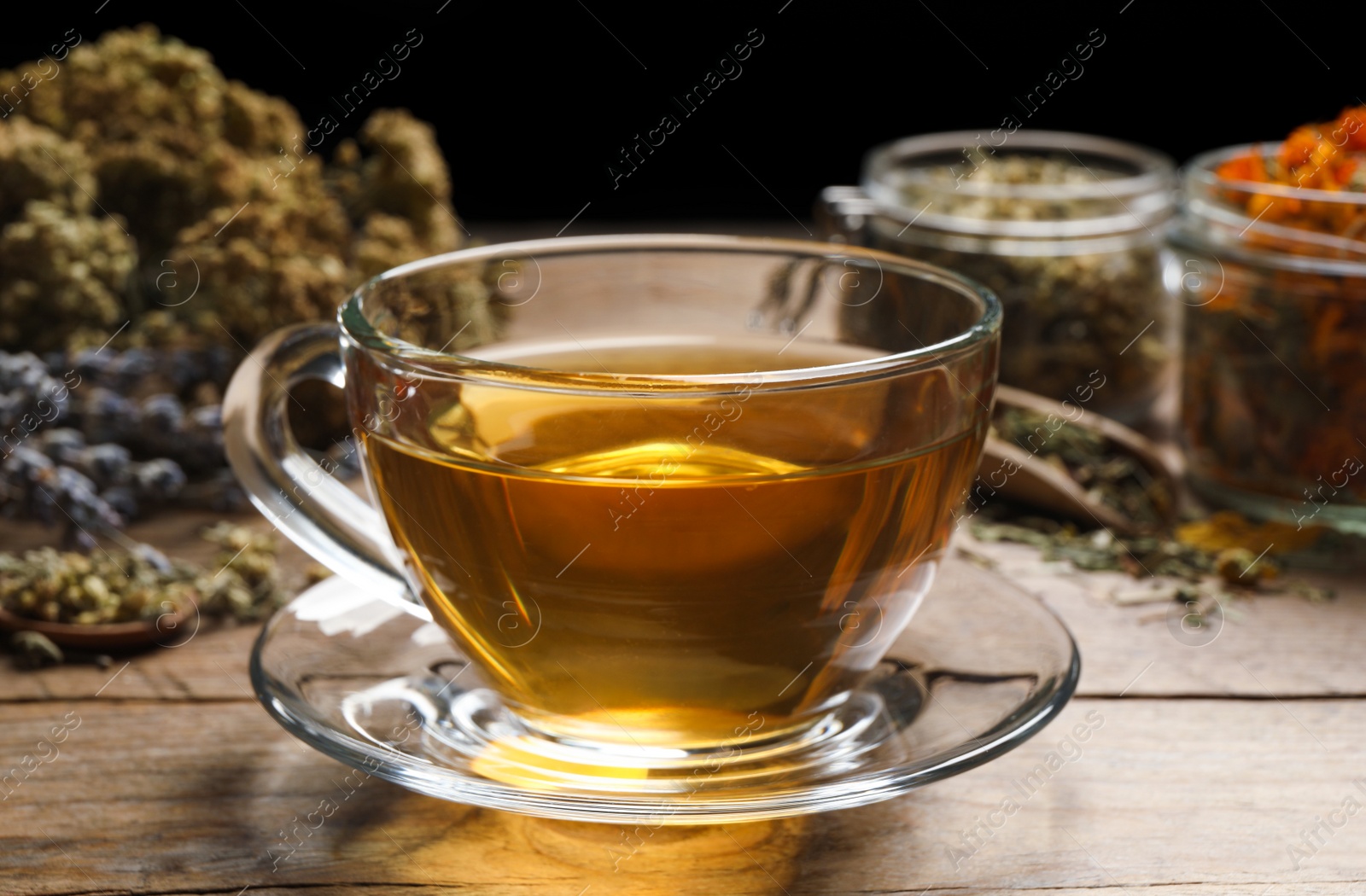 Photo of Freshly brewed tea and dried herbs on wooden table