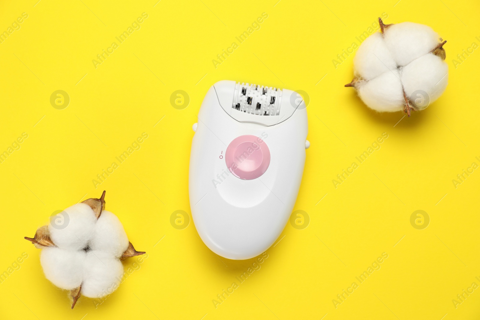 Photo of Modern epilator and fluffy cotton flowers on yellow background, flat lay