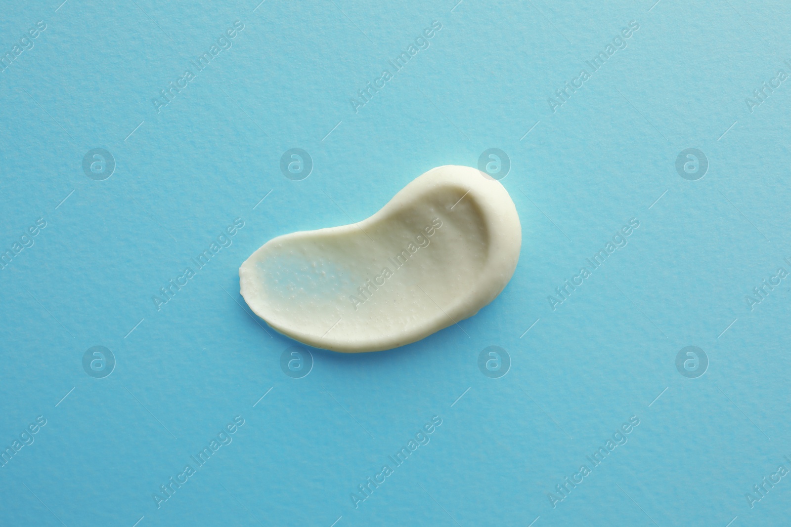 Photo of Sample facial cream on turquoise background, top view