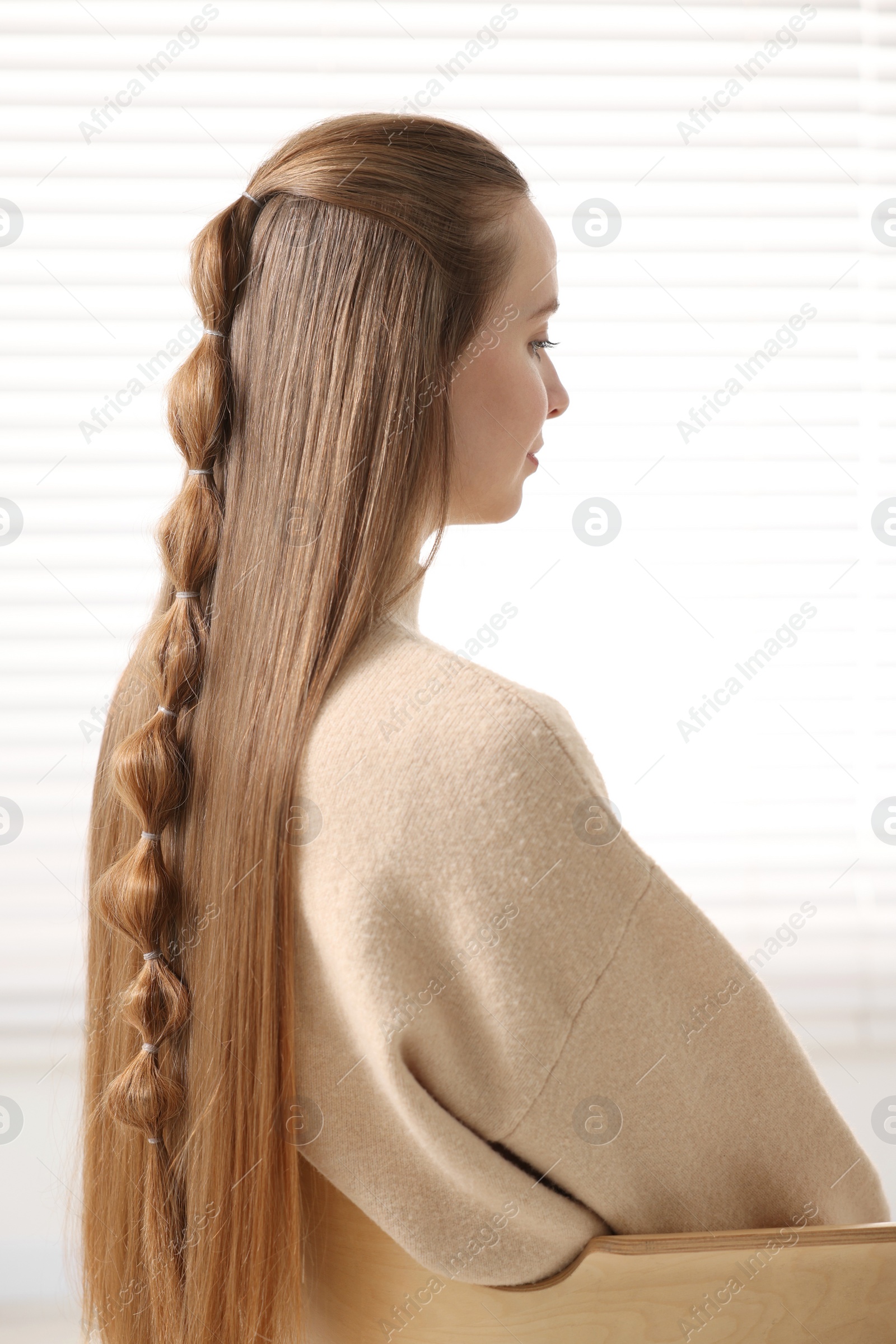 Photo of Young woman with long braided hair indoors