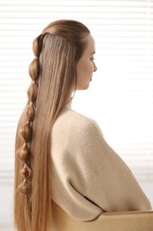 Young woman with long braided hair indoors