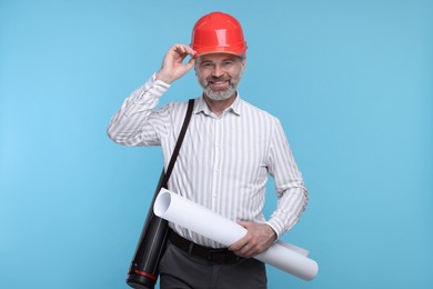 Photo of Architect in hard hat holding draft on light blue background