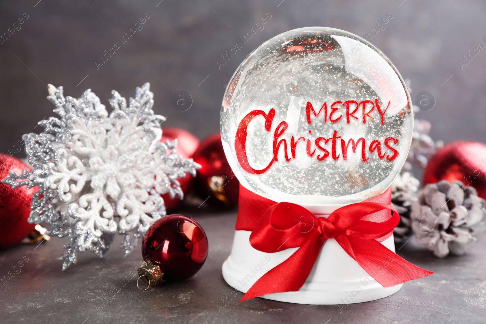 Beautiful snow globe with phrase Merry Christmas and festive decor on grey table Image of Beautiful snow globe with phrase Merry Christmas and festive decor on grey table