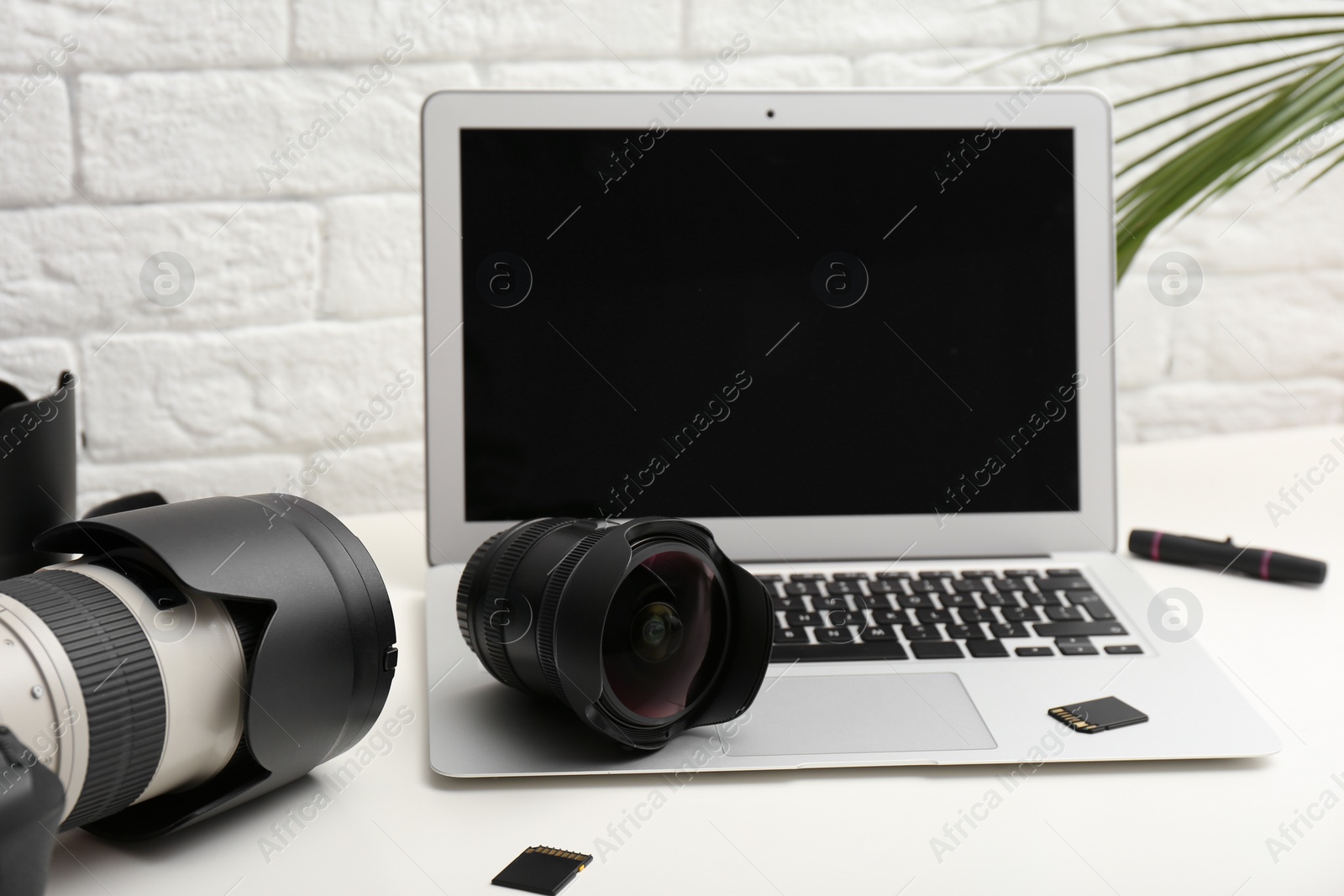 Photo of Laptop and professional photographer's equipment on table indoors. Space for text