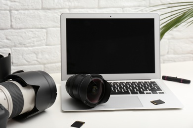 Laptop and professional photographer's equipment on table indoors. Space for text