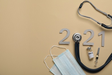 Photo of Paper number with stethoscope forming 2021, vial and space for text on beige background, flat lay. Coronavirus vaccination