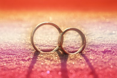 Image of Double exposure of lesbian flag and wedding rings on sandy beach, closeup