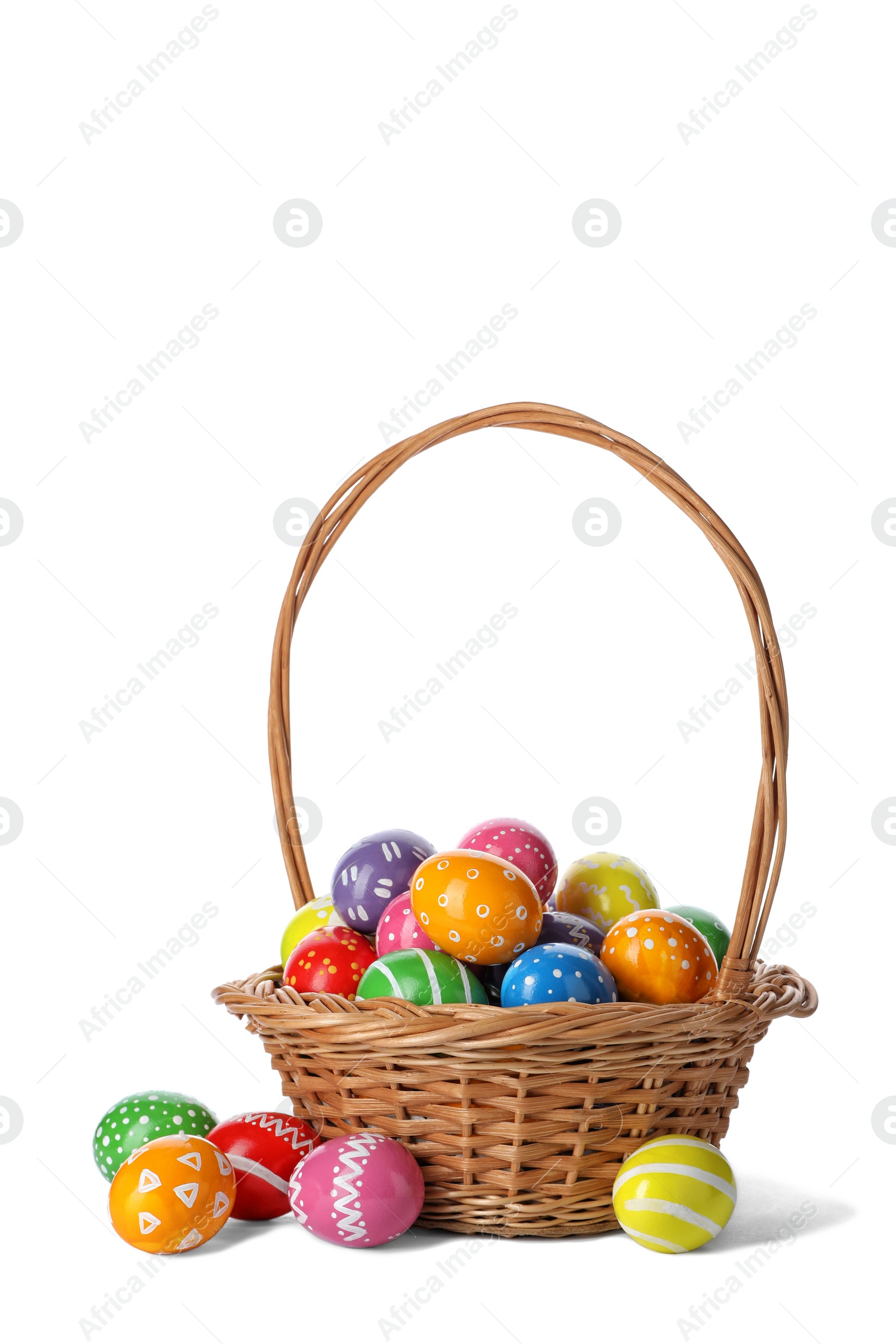 Photo of Decorated Easter eggs in wicker basket on white background