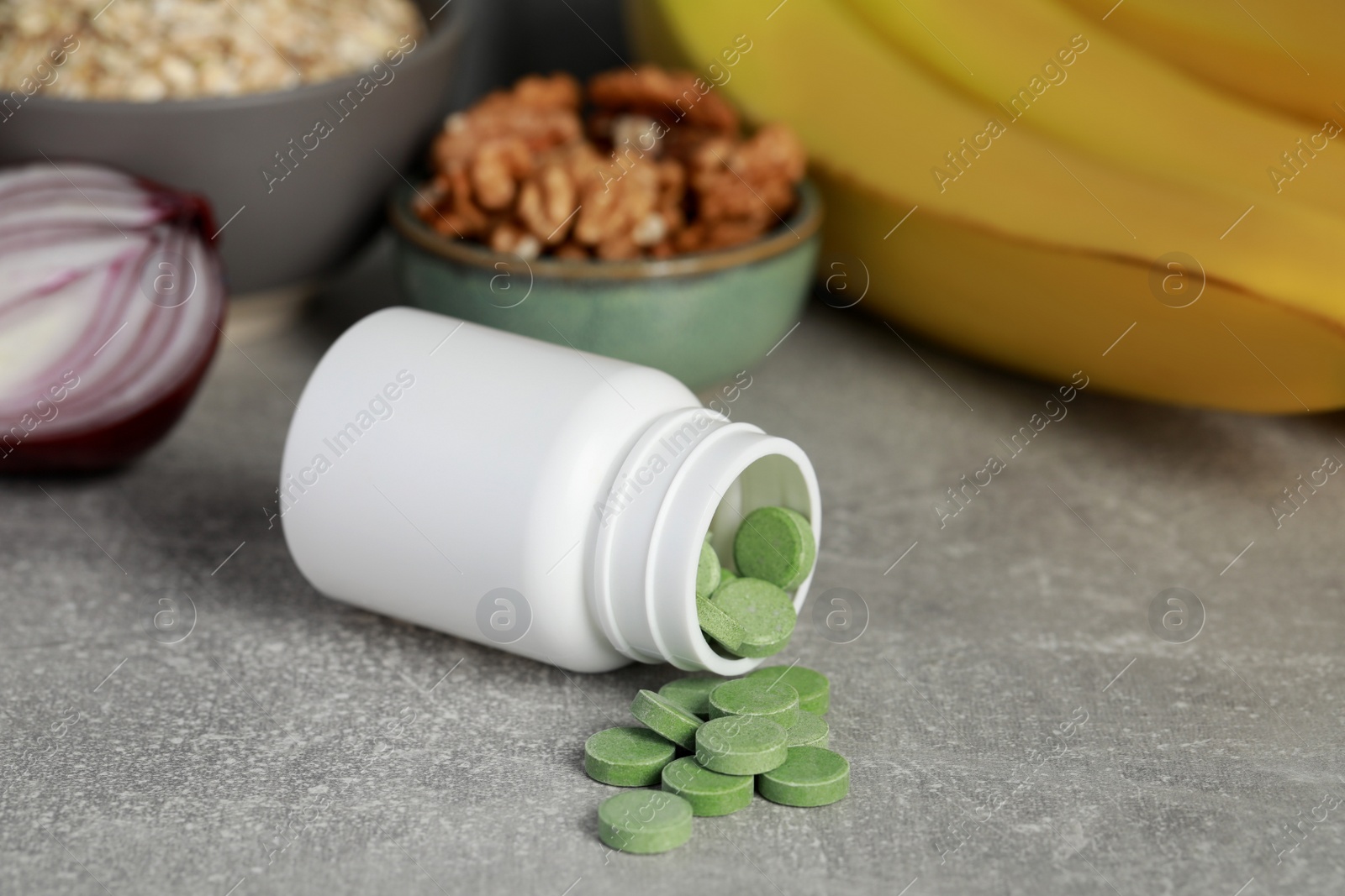 Photo of Bottle of pills near foodstuff on grey table. Prebiotic supplements