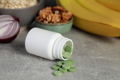 Bottle of pills near foodstuff on grey table. Prebiotic supplements