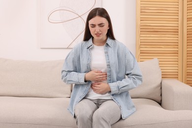 Young woman suffering from stomach pain at home