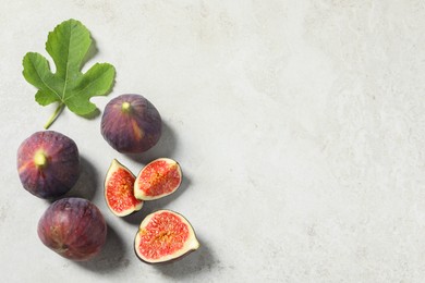 Photo of Fresh ripe figs and green leaf on light table, flat lay. Space for text
