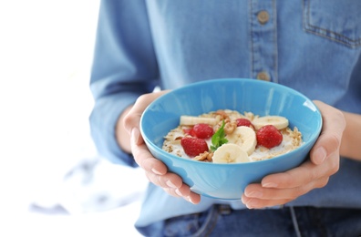Photo of Woman holding bowl with delicious oatmeal and fruits, closeup. Healthy diet