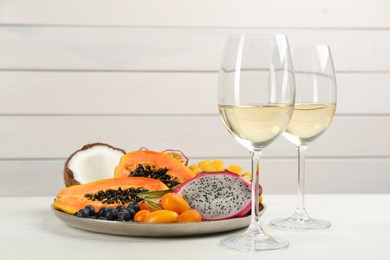 Photo of Delicious exotic fruits and wine on white wooden table