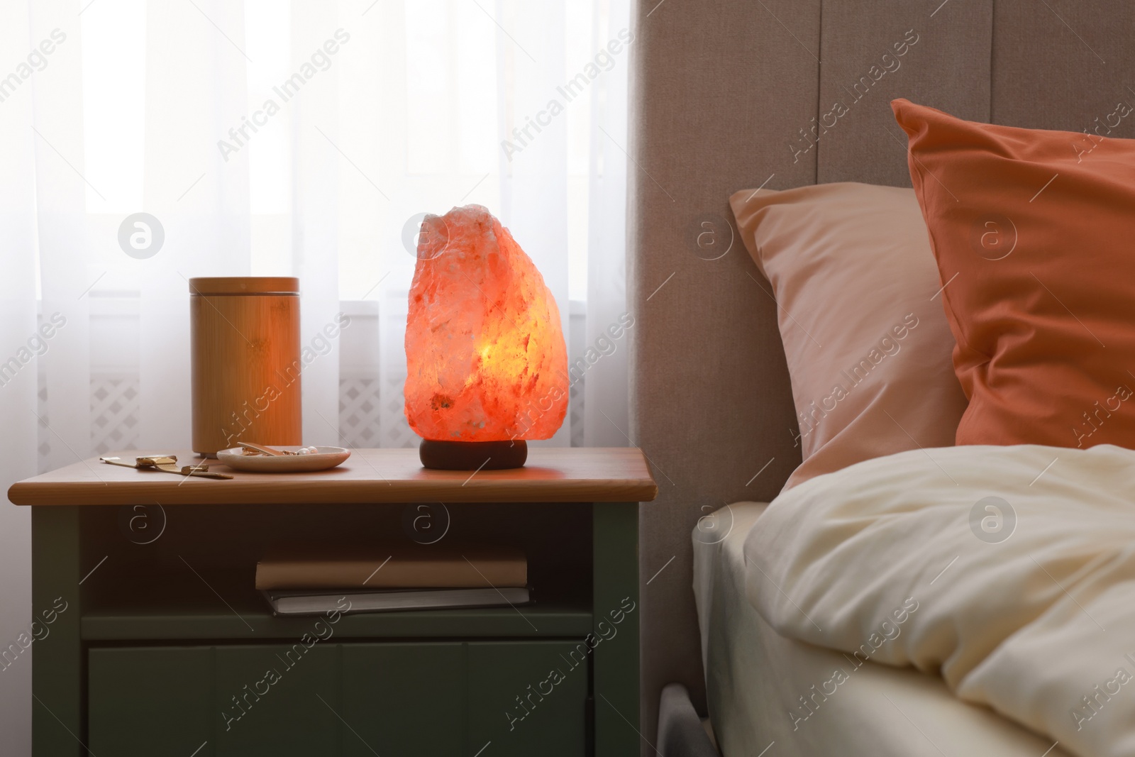 Photo of Himalayan salt lamp, air ionizer and accessories on nightstand in bedroom