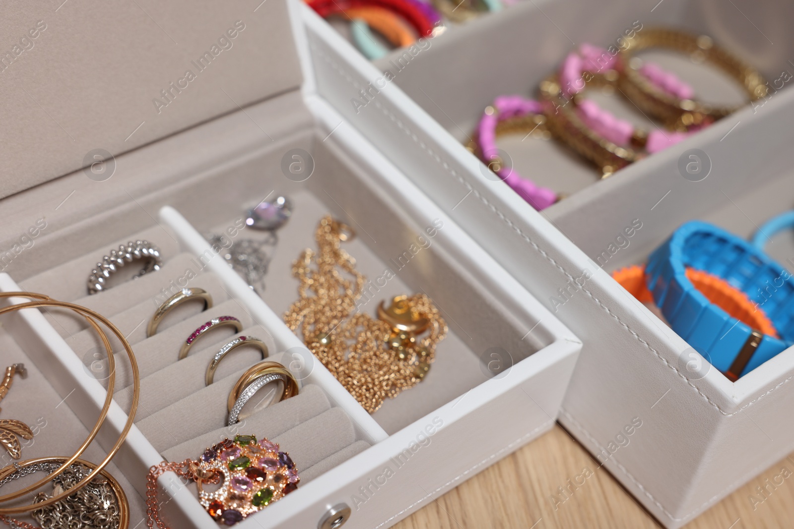 Photo of Jewelry boxes with stylish bracelets and other accessories on wooden table, closeup