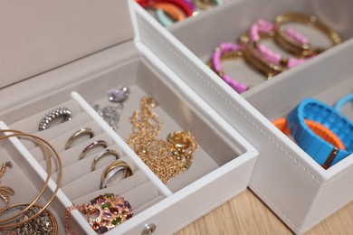 Jewelry boxes with stylish bracelets and other accessories on wooden table, closeup